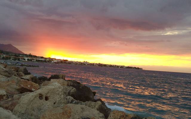Sunset over the sea beyond a rocky shore