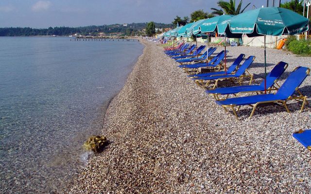 Ipsos Beach: clear water, smooth pebbles and sun loungers